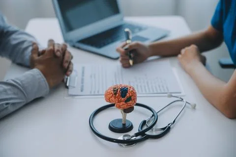 Doctor explaining brain functions to patient on model in office. 写真素材