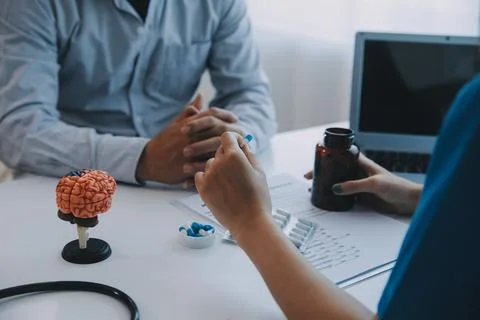 Doctor explaining brain functions to patient on model in office. 写真素材