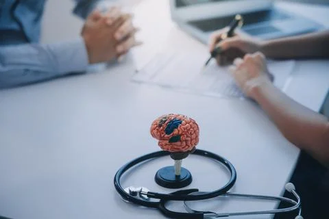 Doctor explaining brain functions to patient on model in office. 写真素材