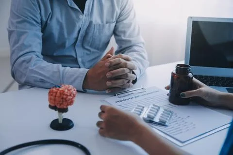 Doctor explaining brain functions to patient on model in office. 写真素材