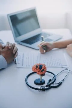 Doctor explaining brain functions to patient on model in office. Foto stock