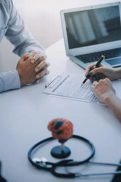 Doctor explaining brain functions to patient on model in office. 写真素材