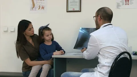 Doctor explaining chest xray image to mother holding little daughter in her arms Stock Footage 72395085