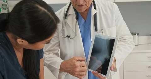 Doctor explaining knee injury while holding tablet computer with x-ray Stock Footage 101398994