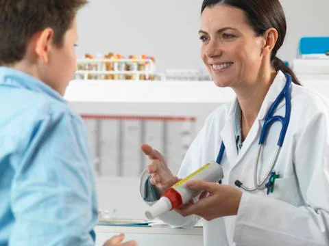 Doctor explaining lung function test to young boy in clinic Stock Photos