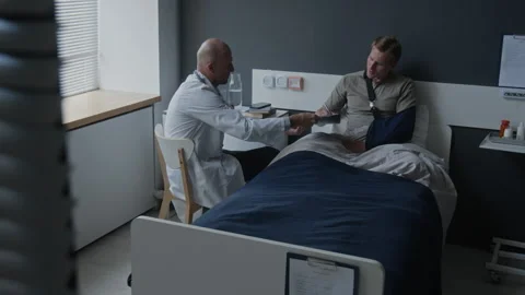 Doctor Explaining Medical Document to Man with Injured Arm in Hospital Stock Footage 340635067