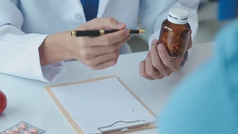 Doctor explaining medication with pen and bottle in medical consultation 스톡 동영상 325477557