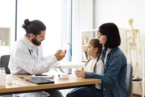 Doctor explaining nebulizer use to mother and young girl at clinic Stock Photos