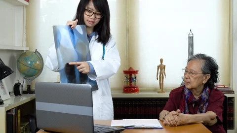 Doctor explaining x-ray to old woman patient and encouraging her Stock Footage 111297007
