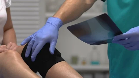 Doctor explaining x-ray results to patient with compression knee brace, trauma Stock-Footage 117387413