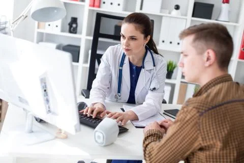 The doctor explains the problem to the patient on the computer. Stock Photos