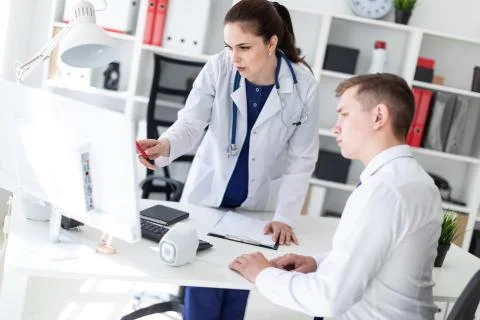The doctor explains the problem to the patient on the computer. Stock Photos