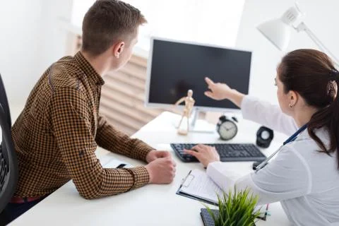The doctor explains the problem to the patient on the computer. Stock Photos