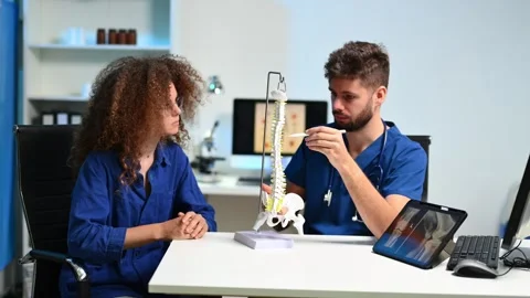 Doctor explains spinal anatomy with model and X-ray to patient during consu.. Stock Footage 312383518