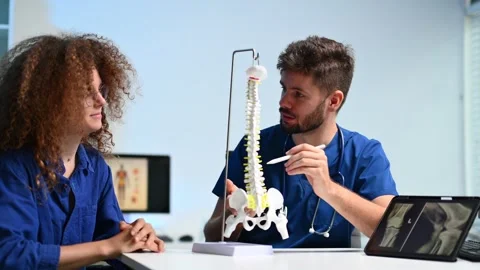 Doctor explains spinal anatomy with model and X-ray to patient during consu.. Stock Footage 312383523