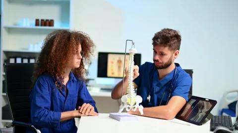 Doctor explains spinal anatomy with model and X-ray to patient during consu.. Stock Footage 312386727