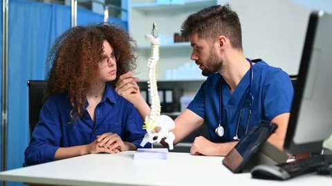 Doctor explains spinal anatomy with model and X-ray to patient during consu.. Vídeos de archivo 312386762