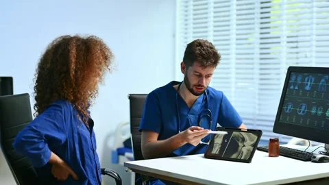 Doctor explains spinal anatomy with model and X-ray to patient during consu.. Stock Footage 312386784