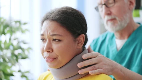 Doctor fixing cervical collar to woman's neck, discomfort, muscular dystrophy Stock Footage 220528894