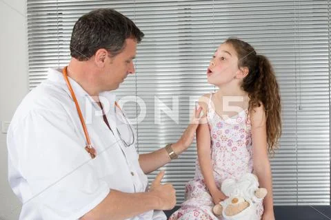 Doctor giving checkup to young girl in exam room Stock Photos