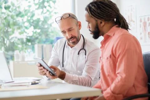 Doctor giving consultation to patient using digital tablet Stock Photos