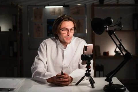 Doctor with glasses using mobile phone camera recording video for followers i Stock Photos