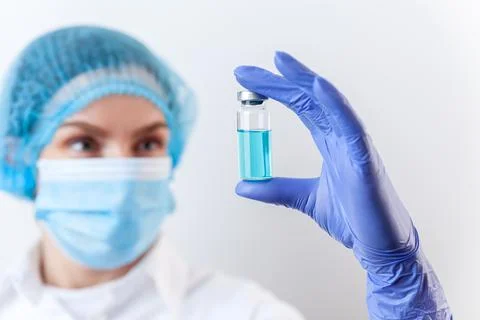 Doctor in gloves and mask holds bottle with vaccine, medicine Stock Photos