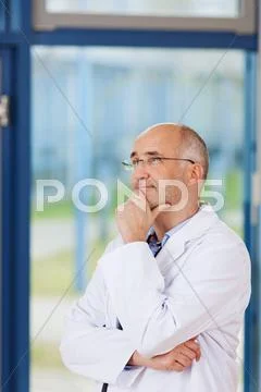 Doctor with hand on chin looking away Stock Photos