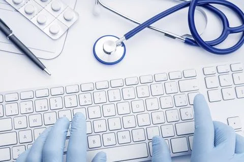 Doctor Hands in gloves typing on computer keyboard on white desk. Telemedicine Stock Photos
