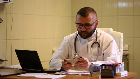Doctor having a break in work and playing games on smartphone Stock Footage 77886480