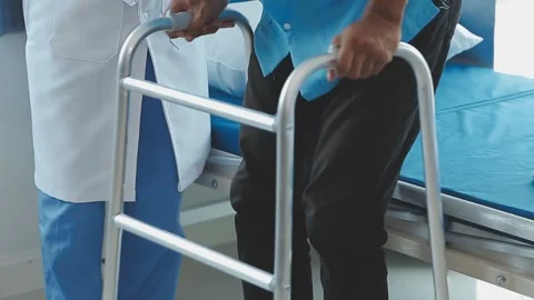 Doctor helping elderly man with walking aid for mobility issues Stock Footage 325445488