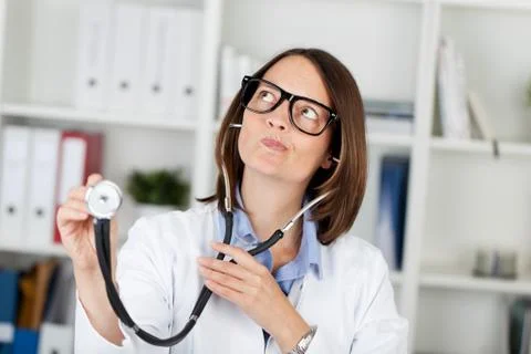 Doctor holding stethoscope while making faces Stock Photos