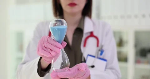 Doctor holds hourglass timer symbolizing importance of time management in Stock Footage 270904329