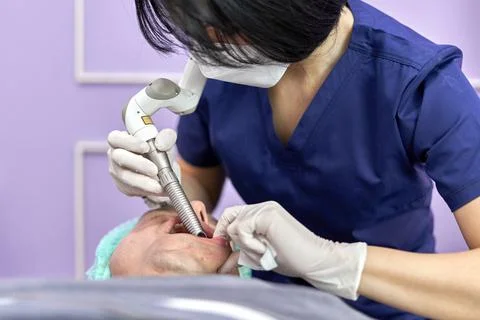 Doctor inserting a laser device into a patient's mouth for a beauty treatment Stock Photos