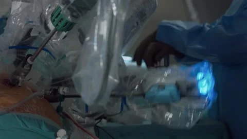 Doctor inserts robotic arm tool into patient's abdomen to perform surgery Stock Footage 245373025