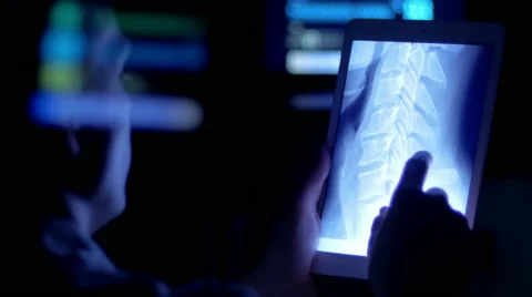 Doctor inspecting an x-ray of a patient on a tablet late at night Stock Footage