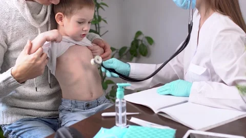 Doctor is inspectioning a boy patient while listening to him using a stethoscope Stock Footage 194465620
