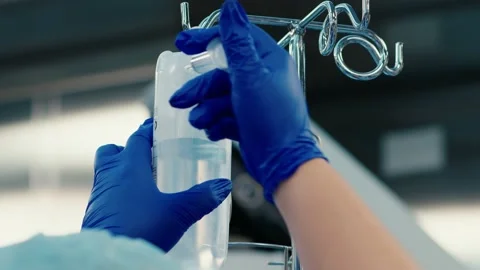 The doctor installs a drip with a solution on a blurred background of surgery Stockbeeldmateriaal 229720655