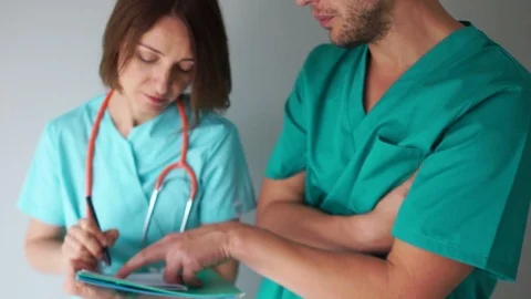 The doctor instructs the assistant. Two young doctors are discussing Stock Footage 118461289