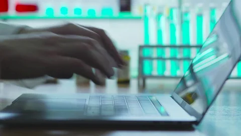 The doctor in the lab typing on notebook report on his research Stock Footage 82997324