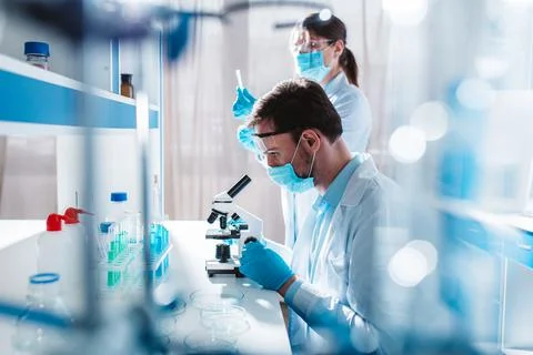 Doctor in the laboratory analyzes samples of codiv-9 under a microscope Stock Photos