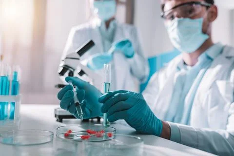 Doctor in the laboratory analyzes samples of codiv-9 under a microscope Stock Photos