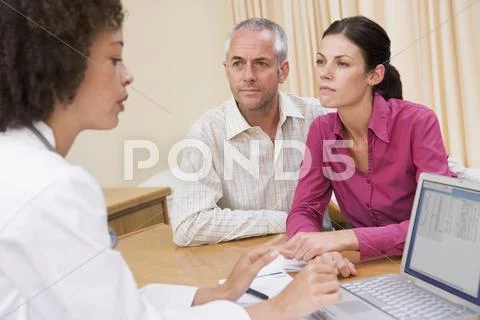 Doctor with laptop and couple in doctor's office frowning Stock Photos