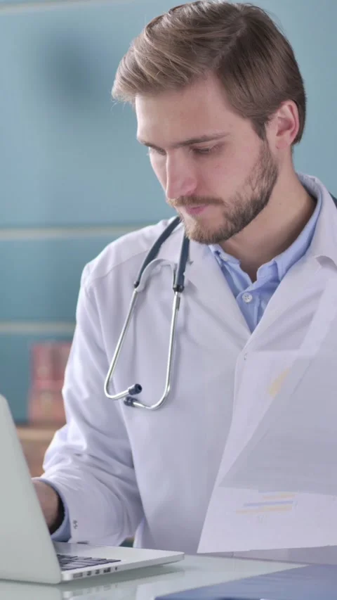 Doctor with Laptop Reading Documents in Office, Vertical Video Vídeo Stock 339580090