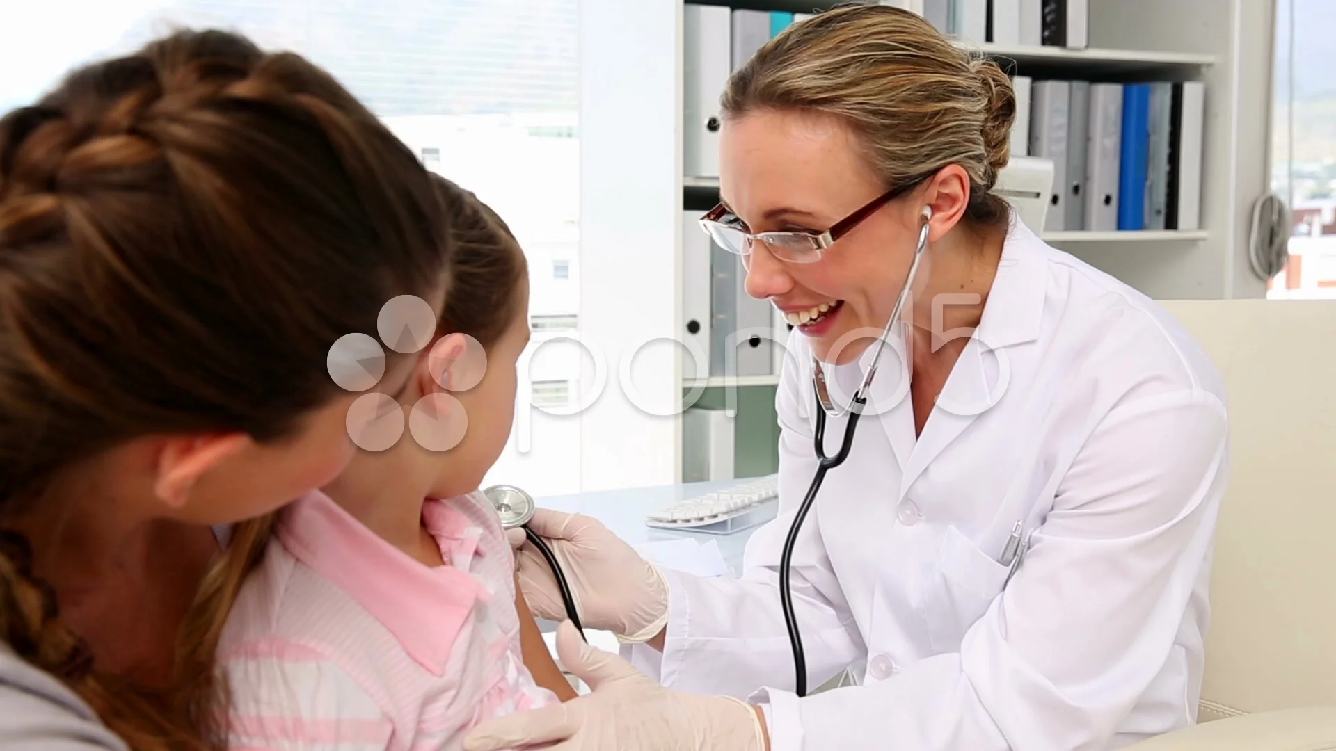 Doctor listening to young girls chest with stethoscope, Stock