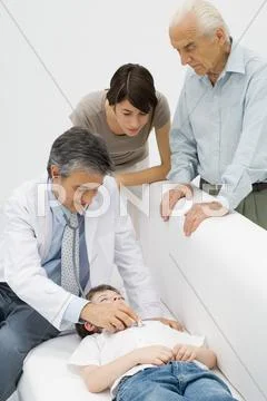 Doctor Listening To Young Patient\'s Heart, Family Watching