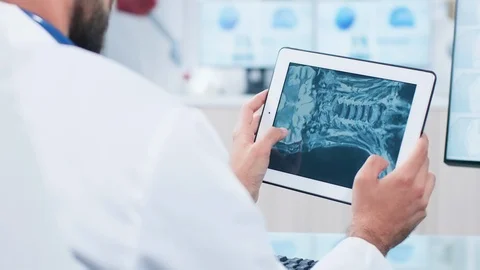 Doctor looking and analyzing a X ray on a digital tablet pc screen Stock Footage 108584266
