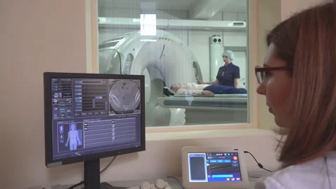 Doctor looking at computer screen while patient moving in mri machine Видео 107490131