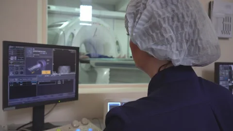 Doctor looking at computer screen while patient moving in mri machine. 4k Видео 107490731
