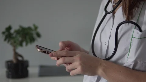 The doctor is looking for information on the phone. Stock Footage 101304028